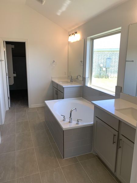 A modern bathroom with a sunken tub, sleek vanity, and natural light filtering through a large window. A modern bathroom with a sunken tub, sleek vanity, and natural light filtering through a large window.