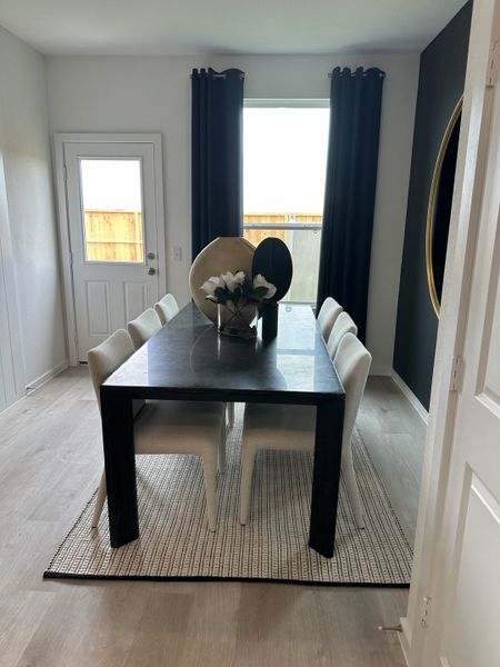 A modern dining area with a sleek black table, white chairs, and elegant decor on a stylish rug.