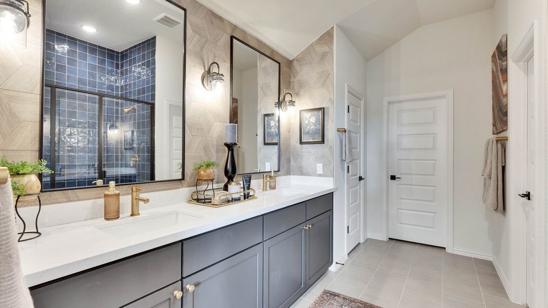 Sophisticated dual vanity with elegant gold fixtures, navy tiled shower, geometric walls in Lakeside Meadows. Sophisticated dual vanity with elegant gold fixtures, navy tiled shower, geometric walls in Lakeside Meadows.