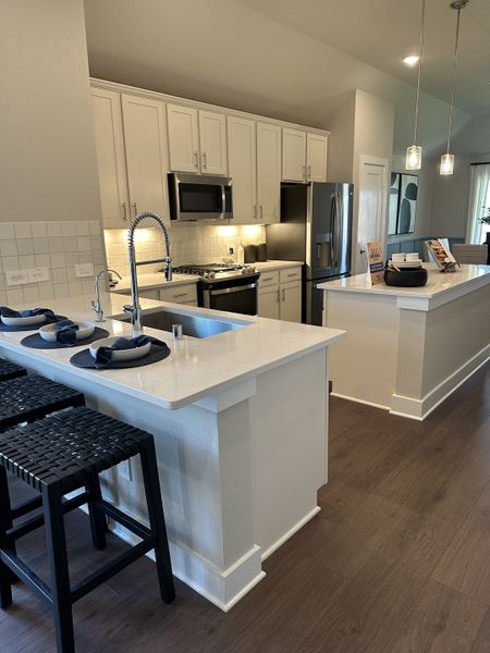 A modern kitchen with sleek white cabinetry, stainless steel appliances, and a spacious island with bar seating. A modern kitchen with sleek white cabinetry, stainless steel appliances, and a spacious island with bar seating.