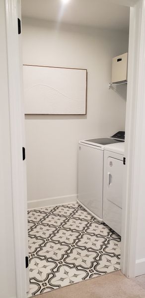 A modern laundry room with decorative patterned tiles, sleek appliances, and minimalistic decor.