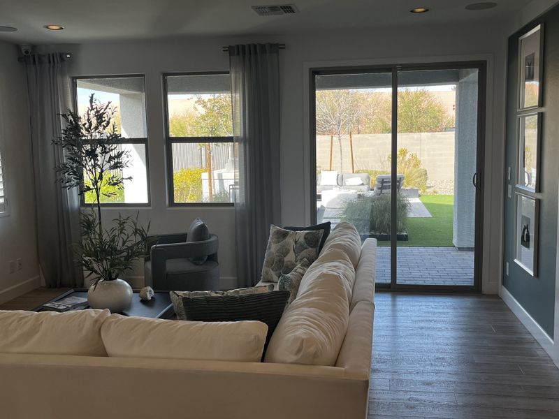 A modern living room with an L-shaped sofa, textured accent wall, and warm lighting.