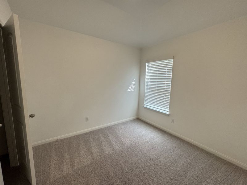 A cozy, carpeted room with neutral walls and natural light filtering through window blinds.