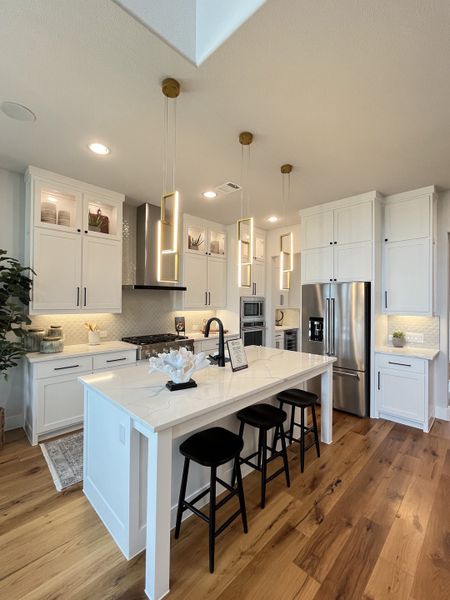 A modern kitchen featuring a spacious island, sleek lighting, and elegant cabinetry with stainless steel appliances.