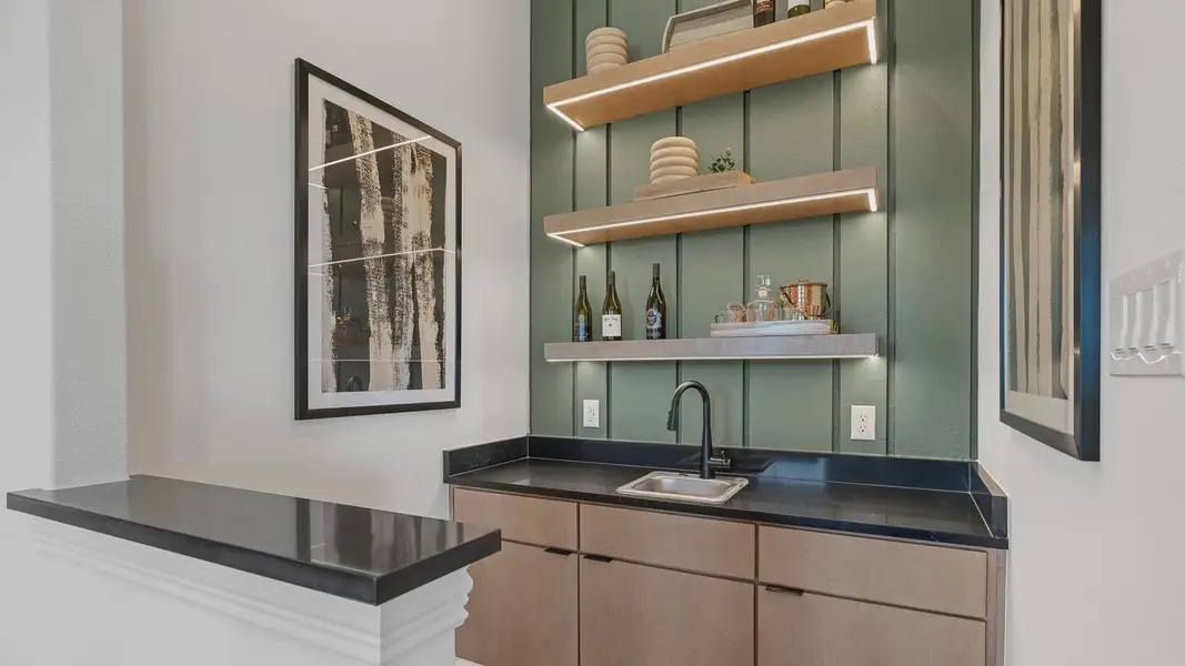 Elegant Southern Pointe bar with floating shelves and black countertop, highlighting minimalist design.