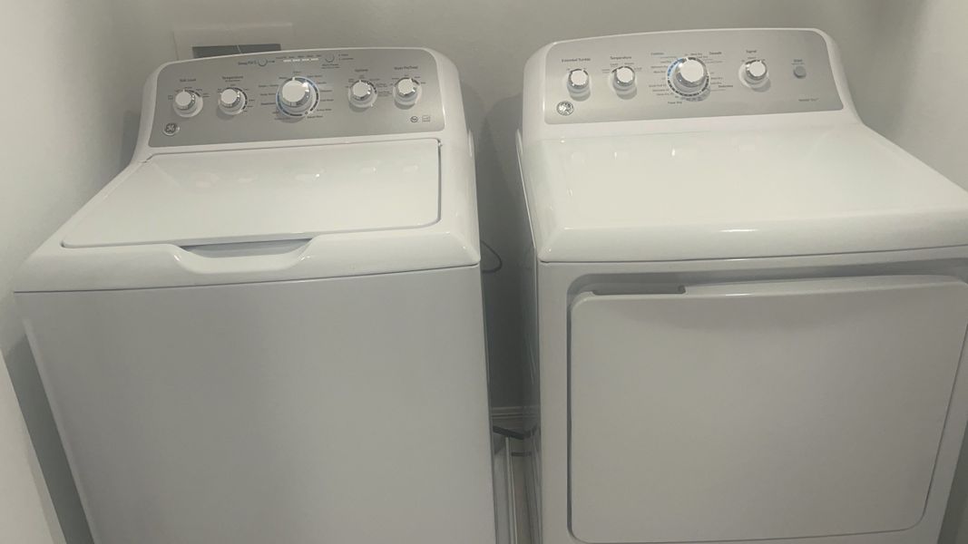 A modern laundry room featuring top-loading washer and dryer in a sleek, minimalist design for efficient utility.
