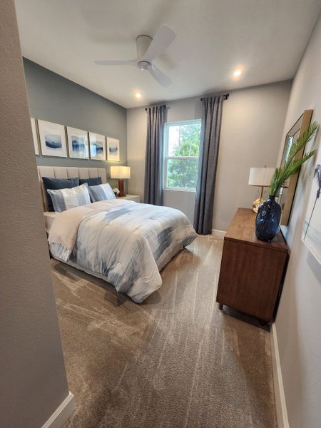 A cozy bedroom with a neutral palette, plush carpeting, and abstract wall art.