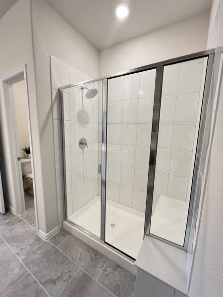 A modern bathroom features a sleek glass shower, white tiles, and elegant gray flooring. A modern bathroom features a sleek glass shower, white tiles, and elegant gray flooring.