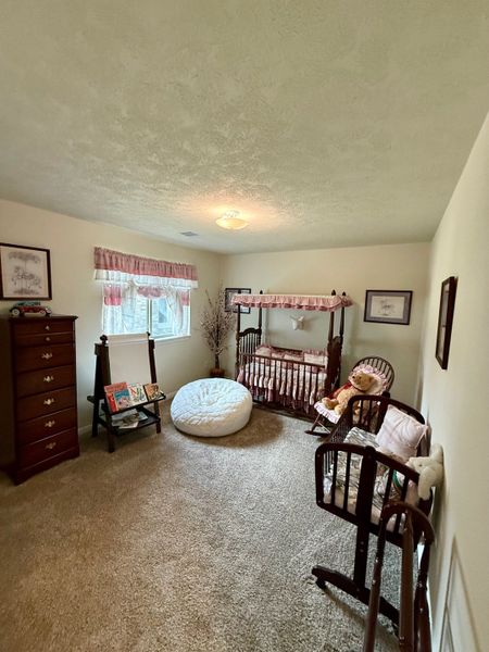 A cozy nursery with a wooden crib, plush seating, soft carpet, and warm lighting. Perfect for a soothing and welcoming space.