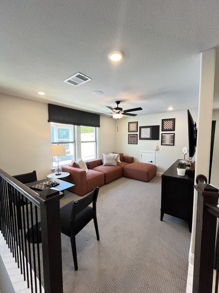 A cozy living area with modern furniture, a ceiling fan, and stylish artwork on the walls.
