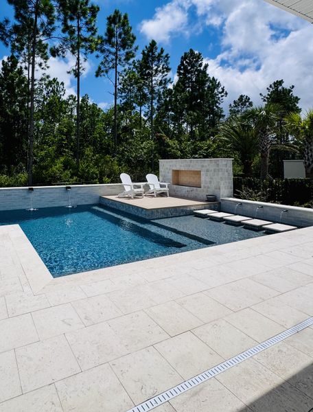 A luxurious poolside with a serene forest backdrop, featuring elegant stone decking and relaxing seating. A luxurious poolside with a serene forest backdrop, featuring elegant stone decking and relaxing seating.
