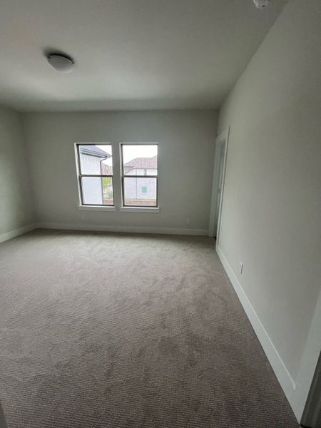 A bright room with soft carpet, large windows, and neutral walls, perfect for a cozy bedroom or an inspiring home office.