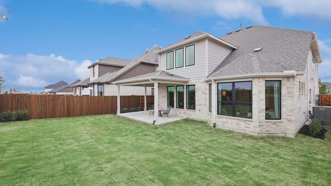 Elegant brickwork and a serene covered patio grace this Wildflower Ranch estate, offering a lush green lawn. Elegant brickwork and a serene covered patio grace this Wildflower Ranch estate, offering a lush green lawn.