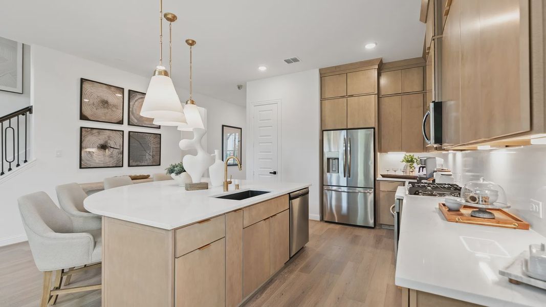 Elegant pendant lights and sleek wood cabinetry define this luxurious Katy Lakes kitchen space. Elegant pendant lights and sleek wood cabinetry define this luxurious Katy Lakes kitchen space.