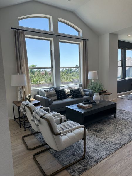 A bright living room featuring a large arched window, cozy seating, and stylish decor on a neutral rug. A bright living room featuring a large arched window, cozy seating, and stylish decor on a neutral rug.