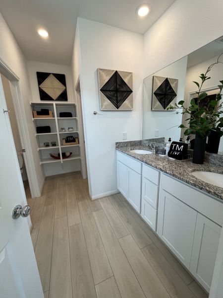 A modern bathroom featuring a granite countertop, dual sinks, light wood flooring, and geometric wall art for a stylish touch. A modern bathroom featuring a granite countertop, dual sinks, light wood flooring, and geometric wall art for a stylish touch.