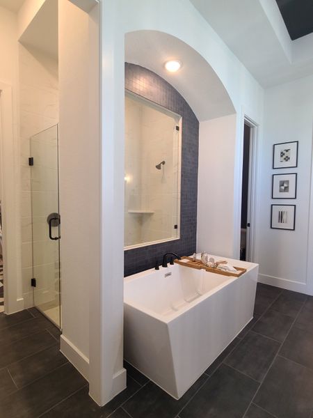 A modern bathroom featuring a sleek tub, blue accent tiles, and elegant lighting, creating a tranquil spa-like retreat.