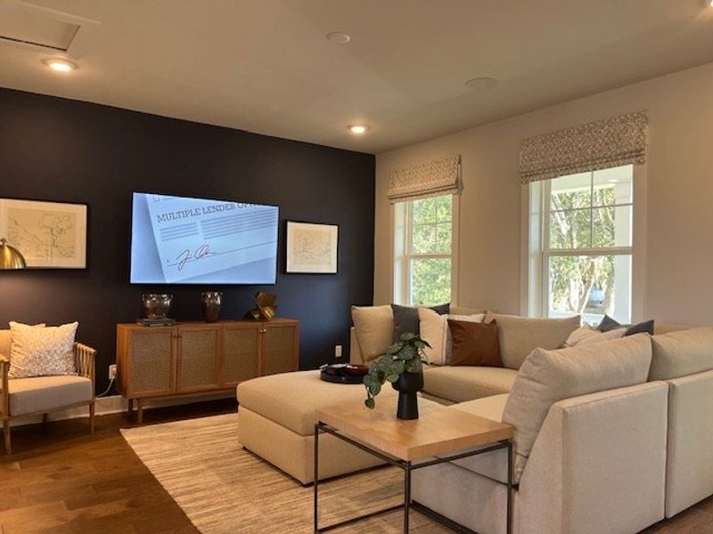 A cozy living room featuring a spacious sectional sofa, dark accent wall, and stylish decor with natural light from large windows.