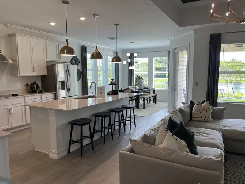 A modern kitchen and dining area with white cabinetry, sleek pendant lights, and an inviting open plan living space.