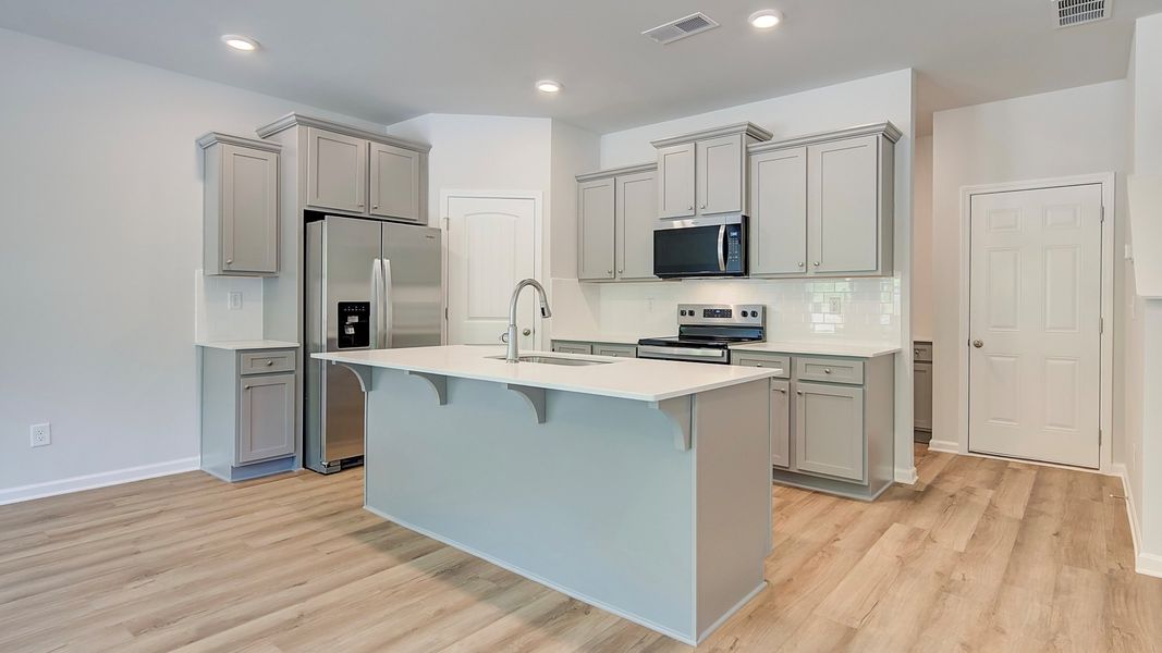 Kitchen with quartz countertops, tile backsplash, and hard surface flooring