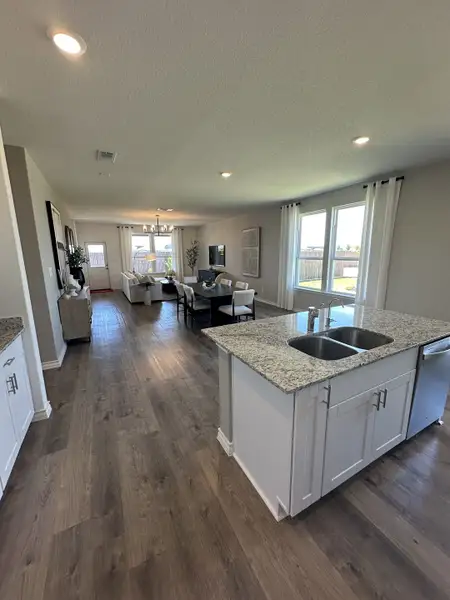 An open-concept living and kitchen area with wood floors, granite countertops, and ample natural light.