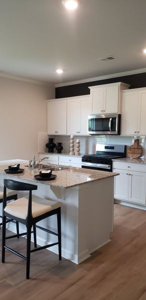 A modern kitchen with granite countertops, sleek white cabinetry, and stylish seating.