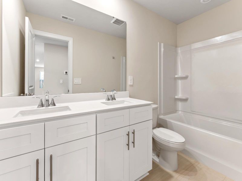 This secondary bathroom features dual-sinks and an oversized shower tub.