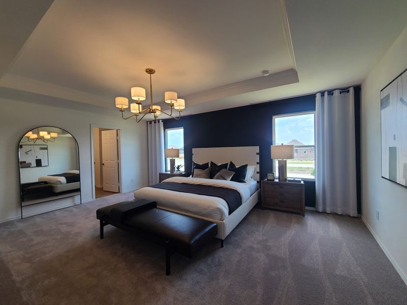 A spacious bedroom featuring a chic chandelier, modern furnishings, and a large window for natural light. A spacious bedroom featuring a chic chandelier, modern furnishings, and a large window for natural light.