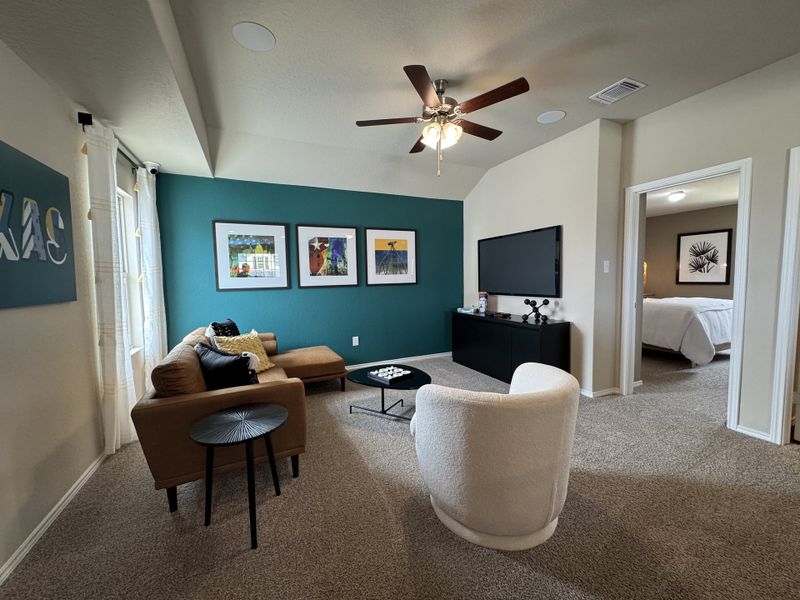 A cozy living room with a teal accent wall, modern artwork, and plush seating for a relaxing ambiance.