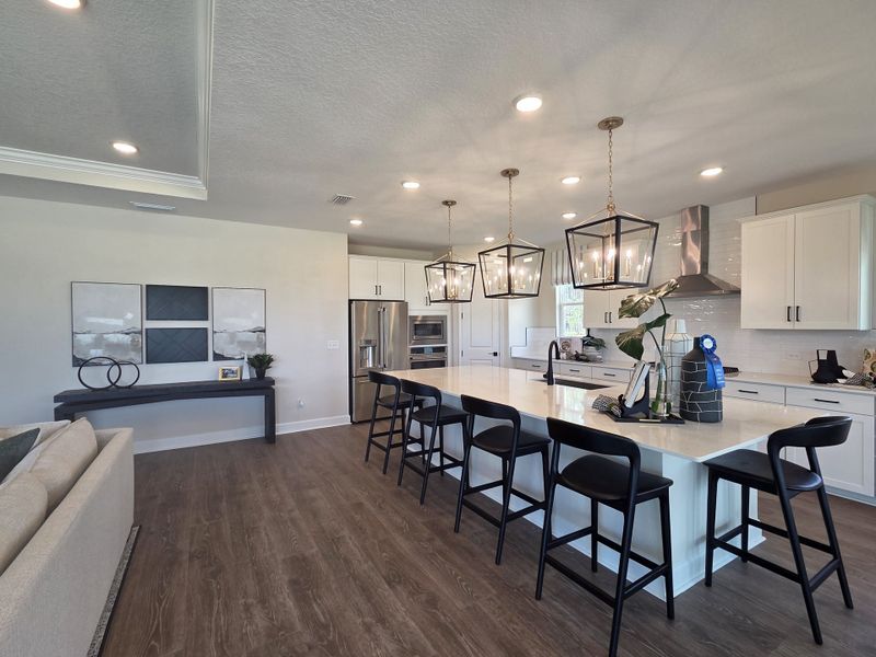A spacious kitchen with an extended island, pendant lighting, and sleek black barstools.