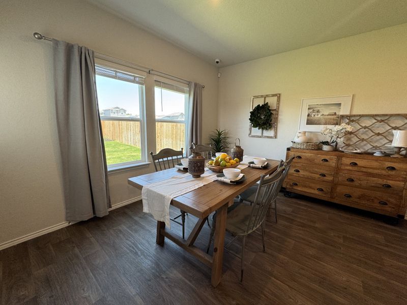 A cozy dining room with a rustic wooden table, modern chairs, and elegant decor, featuring large windows and warm lighting.