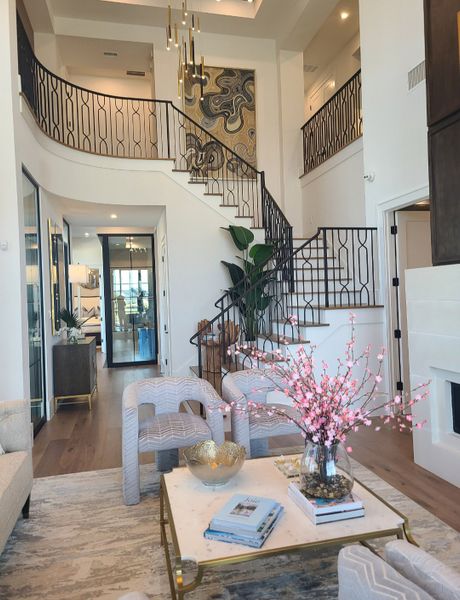 A luxurious living room with a grand staircase, modern art, elegant furniture, and chic lighting fixtures.