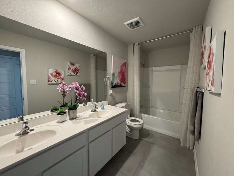 A modern bathroom with dual sinks, floral decor, and a sleek bathtub with a shower curtain.