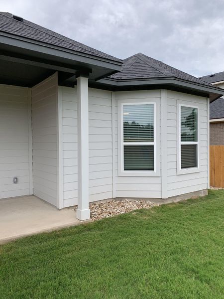 A charming new home exterior with white siding and manicured lawn in Cedar Brook by M/I Homes (Leander, TX).