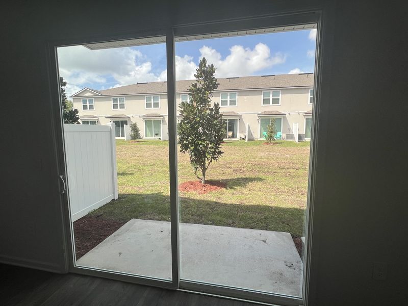 A spacious patio view with a lush green yard seen through large sliding glass doors, perfect for indoor-outdoor living. A spacious patio view with a lush green yard seen through large sliding glass doors, perfect for indoor-outdoor living.