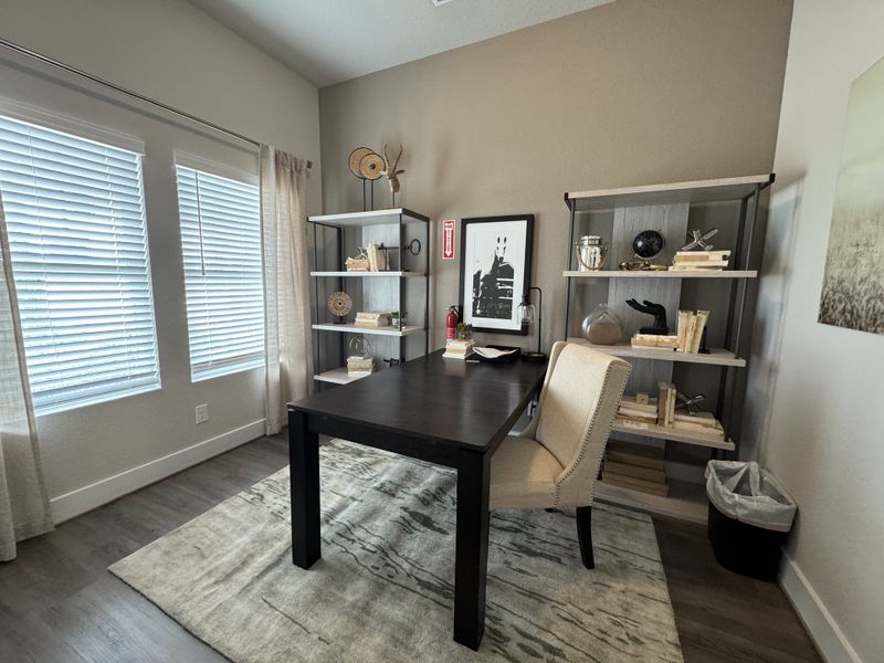 A cozy home office with a sleek dark desk, stylish shelving, and abundant natural light from large windows. A cozy home office with a sleek dark desk, stylish shelving, and abundant natural light from large windows.