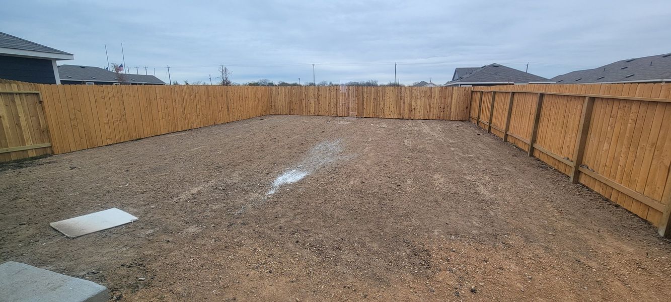 A spacious fenced backyard with bare earth in Saddle Ridge by Rausch Coleman Homes (Lytle, TX).