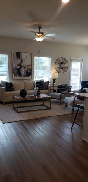 A modern living room with a beige sofa, abstract art, and sleek decor, featuring ample lighting and a stylish ceiling fan. A modern living room with a beige sofa, abstract art, and sleek decor, featuring ample lighting and a stylish ceiling fan.