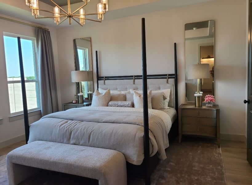 A cozy bedroom with a plush bed, elegant lamps, chic mirrors, and soft lighting.