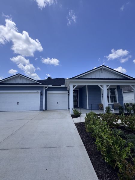 A beautiful blue home with a spacious driveway and manicured landscaping in Hyland Trail by Pulte Homes (Green Cove Springs, FL).