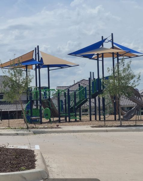 A vibrant playground with sun shades in The Grove Frisco - 40' Lots by Shaddock Homes (Frisco, TX).