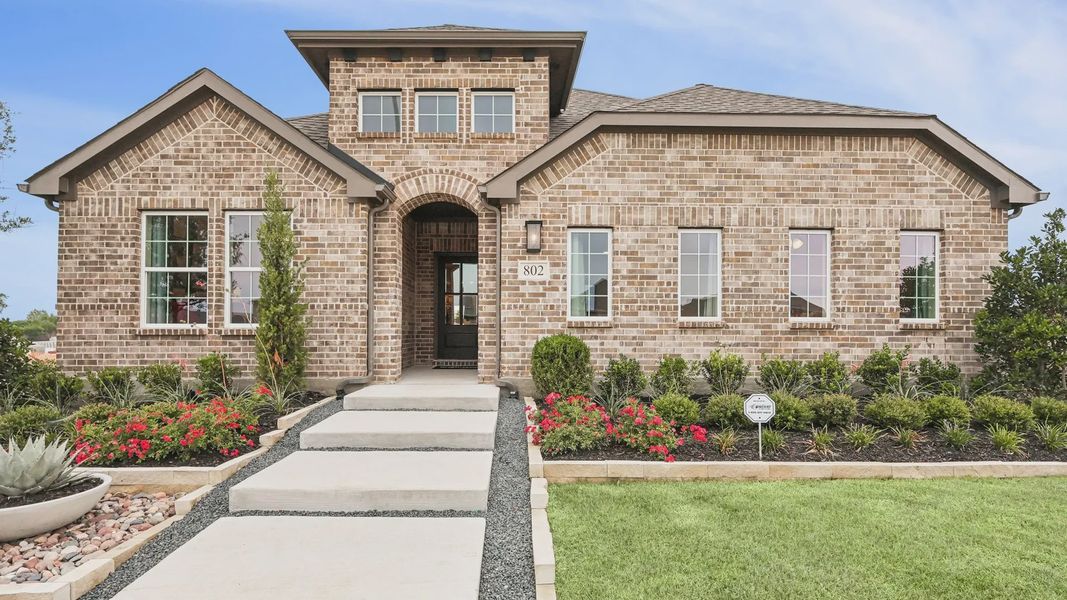 Stunning brick facade with elegant arched entryway and lush gardens at Simpson Crossing.