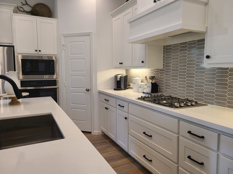 Modern kitchen featuring white cabinets, sleek appliances, and a stylish gray tile backsplash. Modern kitchen featuring white cabinets, sleek appliances, and a stylish gray tile backsplash.