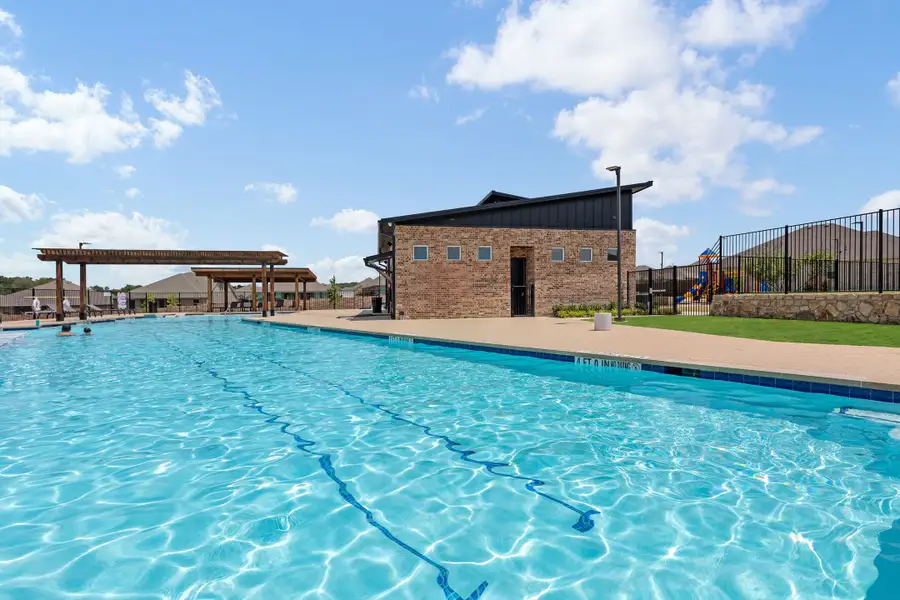 Community pool with brick clubhouse, pergola shade structure, and playground area nearby