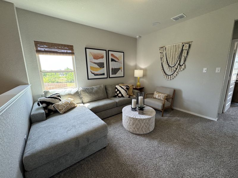A cozy living room featuring a gray sectional, stylish artwork, textured wall decor, and a round coffee table.
