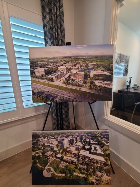 A modern office interior showcasing architectural renderings on easels, complemented by sleek shutters and decor.