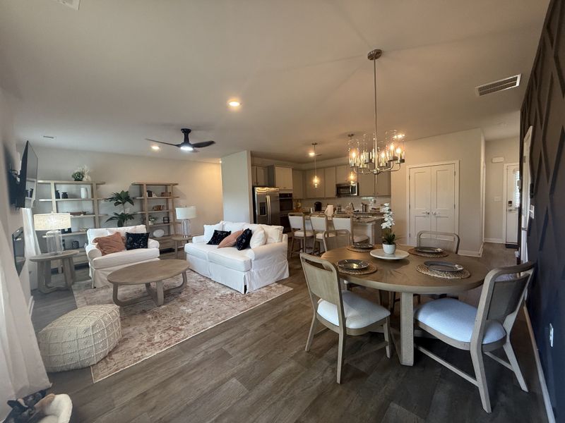 An open-plan living area with cozy seating, chic dining, modern lighting, and wood-inspired flooring. An open-plan living area with cozy seating, chic dining, modern lighting, and wood-inspired flooring.