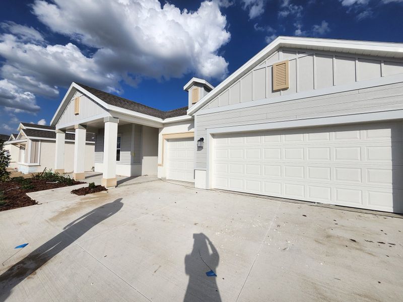 A modern white home with a spacious garage and manicured front yard in Hidden Ridge: Estate Collection by Lennar (Groveland, FL).