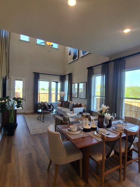 A spacious living and dining area with high ceilings, large windows, and contemporary decor.
