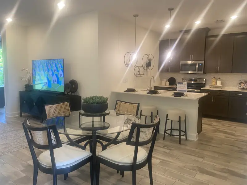 An inviting open-concept kitchen and living area with dark wood cabinets, modern lighting, and a cozy dining space.